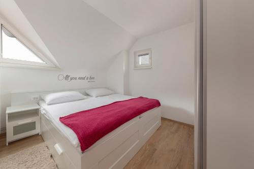 een witte slaapkamer met een bed met een rode deken bij Cadys Apartment in Kranjska Gora