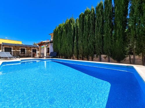 een blauw zwembad in een tuin met bomen bij Villa l'Auba - Charming villa with pool close to Palma and Soller in Bunyola