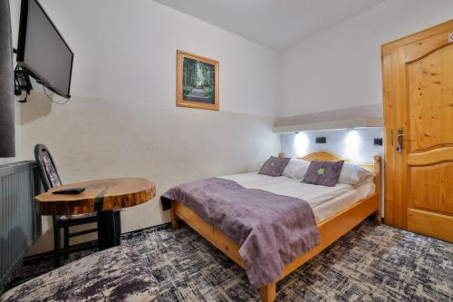 a bedroom with a bed and a table and a tv at Śwarna Wynajem Pokoi in Zakopane