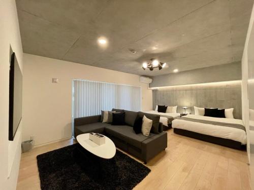 - un salon avec un canapé et 2 lits dans l'établissement bHOTEL Nekoyard - Scenic Penthouse Studio with Jacuzzi & Spacious Terrace, à Hiroshima