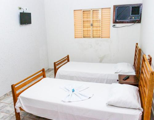 two beds in a room with white sheets at Delta Hotel in Andradina
