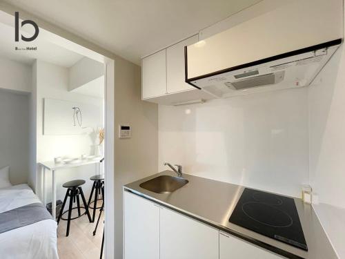 een keuken met een wastafel en een bed in een kamer bij bHOTEL Nekoyard - Brand new 1BR Apt for 7 ppl with loft Few Mins Walk To Peace Park in Hiroshima