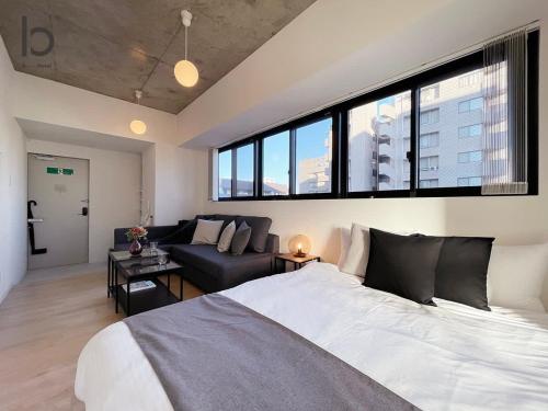 een slaapkamer met een groot bed en een bank bij bHOTEL Nekoyard - Cozy 1BR Apartment, Very Near Peace Park, For 6 Ppl in Hiroshima