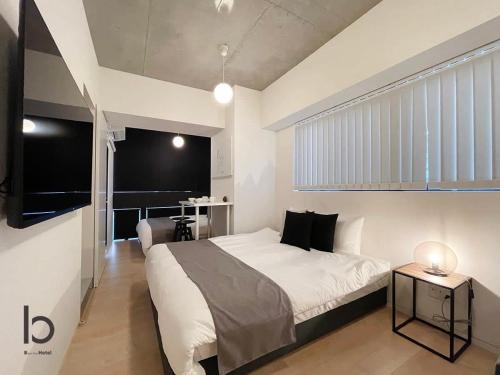 Un dormitorio con una gran cama blanca y una mesa en bHOTEL Nekoyard - 1BR Apartment, Good for 6 Ppl, Near Peace Park, WIFI Available en Hiroshima