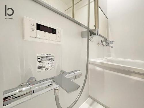 baño blanco con ducha y lavamanos en bHOTEL Nekoyard - New Modern Beautiful 1 BR Apartment, Very Near Peace Park, for 6Ppl en Hiroshima