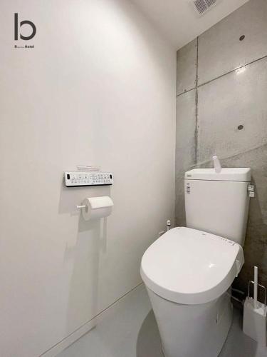 a bathroom with a white toilet in a room at bHOTEL Nekoyard - Modern Loft Studio Near Peace Park & City Center in Hiroshima