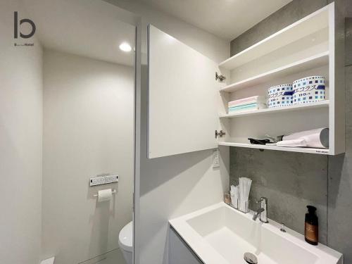 a white bathroom with a sink and a toilet at bHOTEL Nekoyard - Modern Loft Studio Near Peace Park & City Center in Hiroshima