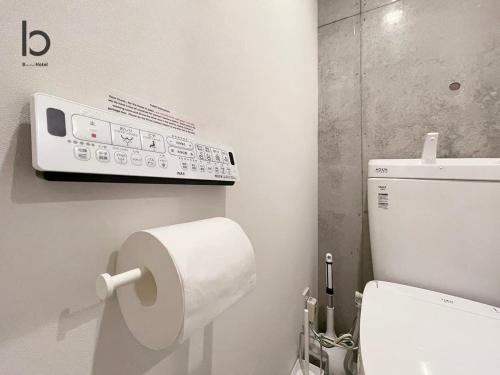 a bathroom with a toilet paper dispenser on the wall at bHOTEL Nekoyard - Modern Loft Studio Near Peace Park & City Center in Hiroshima