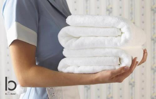 a woman holding a stack of white towels at bHOTEL Nekoyard - Modern Loft Studio Near Peace Park & City Center in Hiroshima