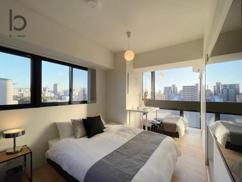 bHOTEL Nekoyard - NEW 1 BR Apartment, Near Peace Park, 6Ppl في هيروشيما: غرفة نوم بسرير كبير ونوافذ كبيرة