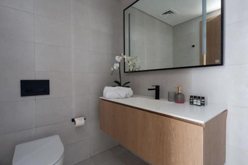 La salle de bains est pourvue d'un lavabo, d'un miroir et de toilettes. dans l'établissement Frank Porter - Marquise Square, à Dubaï