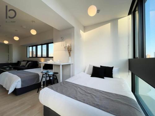 a bedroom with two beds and a living room at b hotel Nekoyard - Convenient Studio, Walk to Peace Park & Shops in Hiroshima