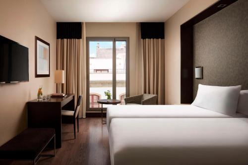 サンタクルス・デ・テネリフェにあるNH テネリフェのベッド、デスク、窓が備わるホテルルームです。