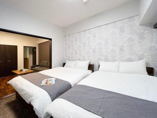 bHOTEL Casaen - Brand New 1BR Apt Near Hondori Shopping District For 6 Ppl في هيروشيما: غرفة فندقية بسريرين وغرفة بها