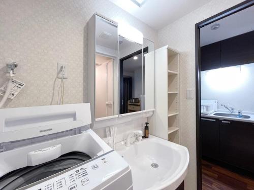 a white bathroom with a sink and a mirror at bHOTEL Casaen - Brand New 1BR Apt Near Hondori Shopping District For 6 Ppl in Hiroshima