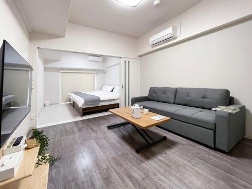 a living room with a couch and a table and a bed at bHOTEL Casaen - 1BR apartment in a quiet neighborhood, near Hondori Shopping Arcade in Hiroshima