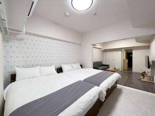 a bedroom with a large bed and a living room at bHOTEL Casaen - Cozy 1BR Apt near Hondori District for 6 Ppl in Hiroshima