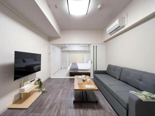 ein Wohnzimmer mit einem Sofa und einem TV in der Unterkunft bHOTEL Casaen - Cozy 1BR Apt near Hondori District for 6 Ppl in Hiroshima