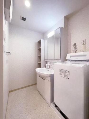 a small white kitchen with a sink and a refrigerator at Casaen - Cozy 1BR Apt near Hondori District for 6 Ppl in Hiroshima