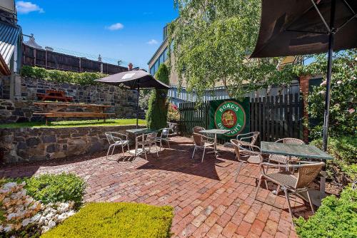 a patio with tables and chairs and an umbrella at Quality Hotel Colonial Launceston in Launceston