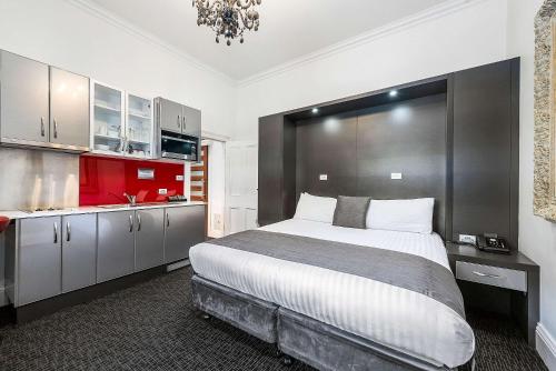 a bedroom with a large bed and a red kitchen at Quality Hotel Colonial Launceston in Launceston