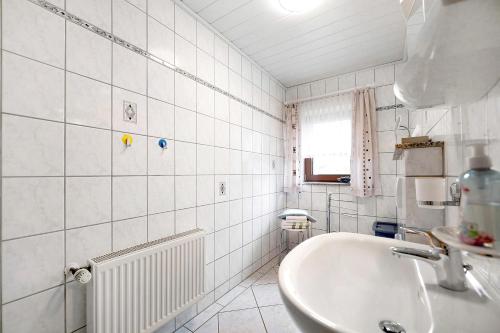 a white bathroom with a sink and a tub at Am Tivoli in Hermeskeil