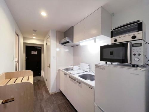 a small kitchen with a sink and a microwave at Casaen by b hotel - Entire Apt for 6Ppl City Center in Hiroshima