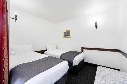 two beds in a room with white walls at Quality Hotel Colonial Launceston in Launceston