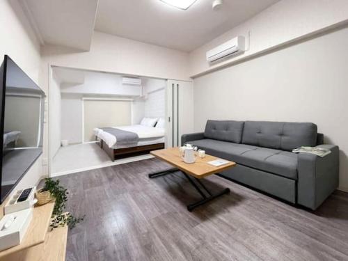 una sala de estar con un sofá y una cama en Casaen by b hotel- Modern 1 BR near Hondori District for 6 Ppl, en Hiroshima