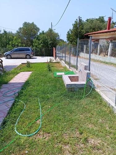 a garden with a bench and a hose on the grass at Johnny 's private house in Néa Michanióna