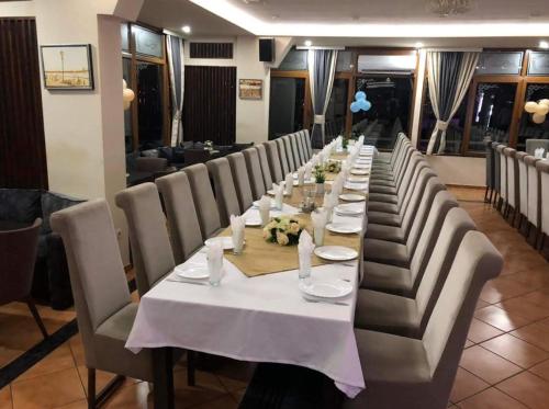 una mesa larga en un restaurante con mesas y sillas blancas en AQUA RESORT en Plav