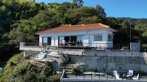 a house on a bridge with people standing on it at bLOCAL Sugawa House - Exclusive Seaside Escape in Ocean House in Kure
