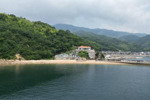 a house on the shore of a body of water at bLOCAL Sugawa House - Exclusive Seaside Escape in Ocean House in Kure