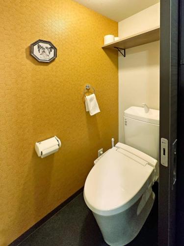 a bathroom with a white toilet in a yellow wall at bHOTEL Nagomi - 1 BR Apt on the 9th flr with City view for 10 Ppl in Hiroshima