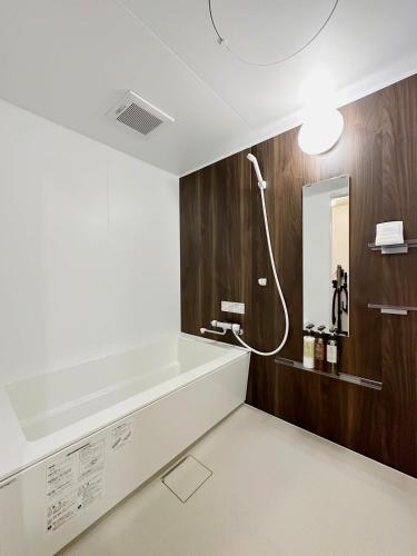 a bathroom with a bath tub and a mirror at bHOTEL Nagomi - Beautiful 2BR Apt City Center for 10 Ppl in Hiroshima