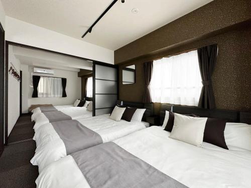a row of white beds in a room at bHOTEL Nagomi - Large 2BR Apt City Center for 10 Ppl in Ōsukachō