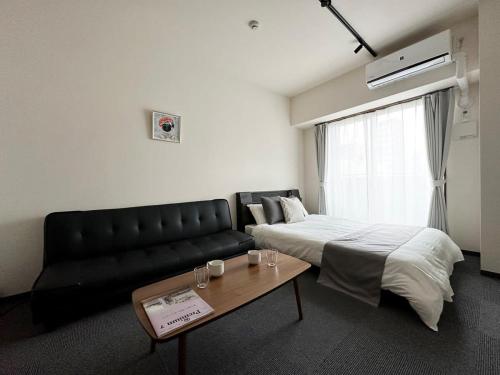 广岛Nagomi by b hotel - Comfy Apartment for 3 people near City Center的一间卧室，里面有一张床、一张沙发和一张桌子