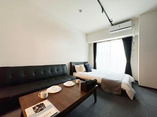 廣島的住宿－bHOTEL Nagomi - Comfy 1 Bedroom in City Center for 3ppl，客房设有床、沙发和桌子。