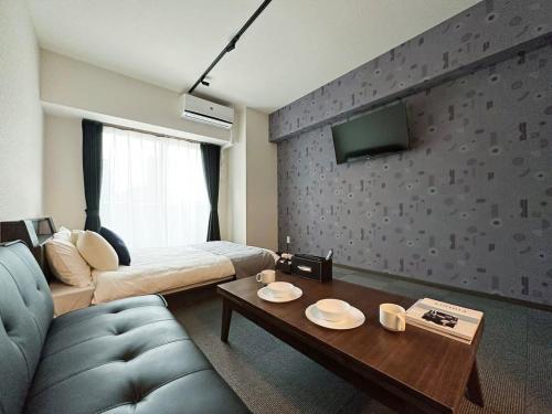 bHOTEL Nagomi - Comfy 1 Bedroom in City Center for 3ppl في هيروشيما: غرفة بها أريكة وسرير وطاولة