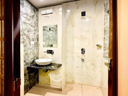 een badkamer met een wastafel en een spiegel bij The NDVL Hotel - Top Rated and Most Awarded Property in Haridwar in Haridwār