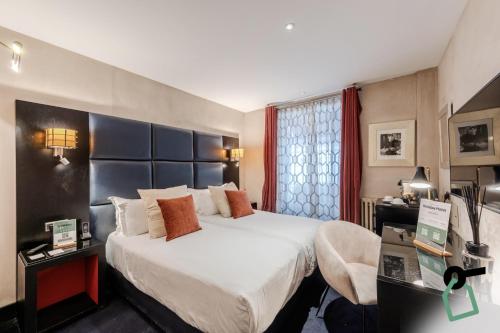 Pokój hotelowy z dużym łóżkiem i biurkiem w obiekcie Hotiday Collection Paris - Arc de Triomphe w Paryżu