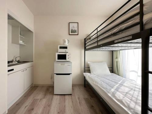 尾道的住宿－bHOTEL Yutori - Attractive 1Br Apt for 4 people in Onomichi，一间小卧室,配有一张双层床和微波炉