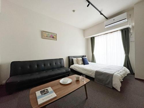 広島市にあるbHOTEL Nagomi - Luxe Apt for 3Ppl City Centerのベッドとソファ付きのホテルルーム