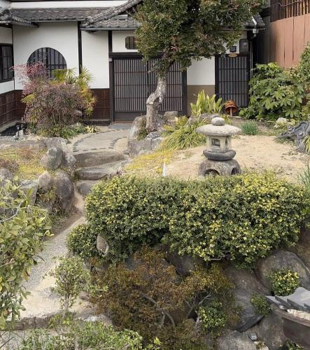 a japanese garden with a stone statue in front of a house at bLOCAL Bingo Yamamo - Experience at Traditional Japanese House in Onomichi