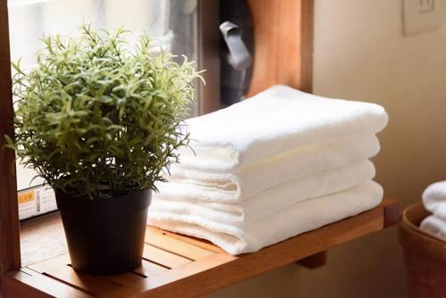 a pile of towels on a table with a potted plant at bLOCAL Bingo Yamamo - Experience at Traditional Japanese House in Onomichi