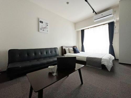 広島市にあるbHOTEL Nagomi - 1 Bedroom Apt in City Centre w balcony for 3 Pplのベッドルーム1室(ベッド1台、ソファ、テーブル付)