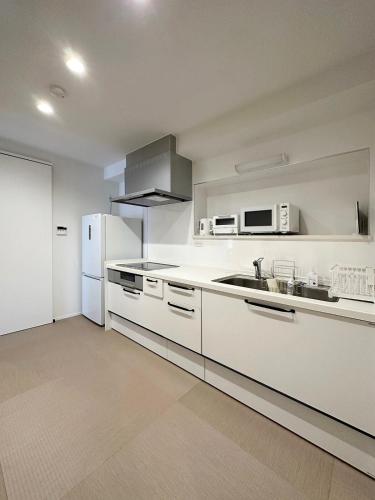 a white kitchen with a sink and a refrigerator at bLOCAL Itsuki - Charming Private House in Miyajimaguchi Near Itsukushima Shrine Upto 18 ppl in Hatsukaichi