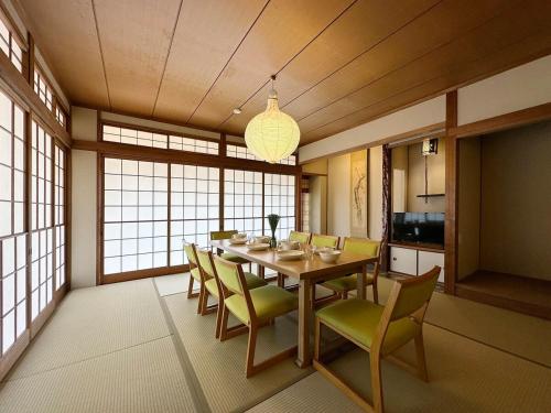 bLOCAL Itsuki - Charming Private House in Miyajimaguchi Near Itsukushima Shrine Upto 18 ppl في هاتسوكايتشي: غرفة طعام مع طاولة وكراسي طويلة