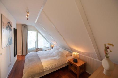 1 dormitorio con 1 cama blanca en el ático en De Mors Bungalow nabij zwembad en golfbaan, en Delden