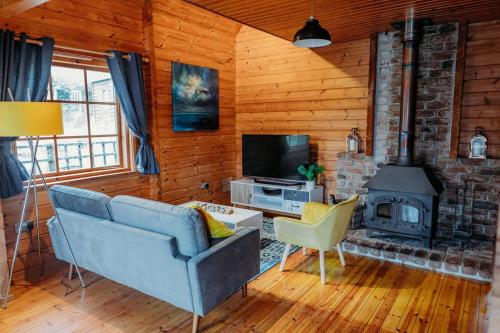 a living room with a blue couch and a fireplace at Finlodge- Pet-Friendly Scandinavian Cabin in Callington